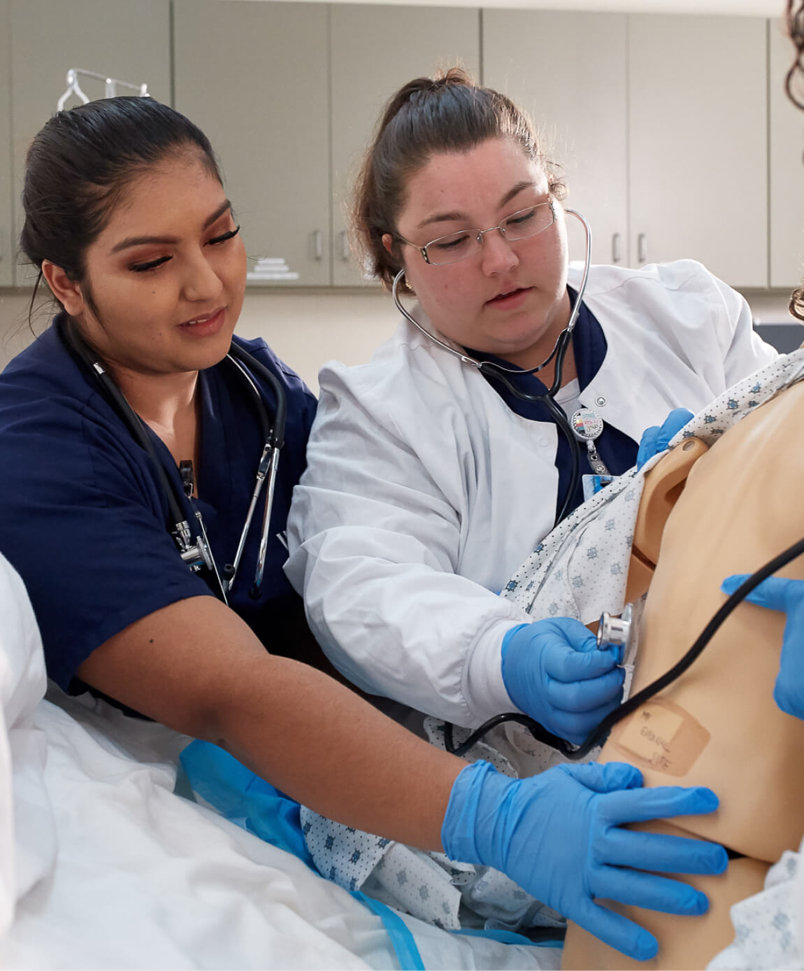 students practicing listening to patient's heartbeat on mannequin